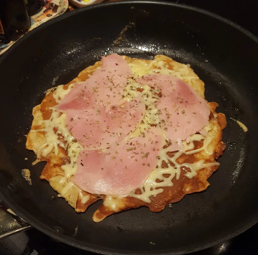 Pannekakepizza med smeltet ost og skinke i stekepanna